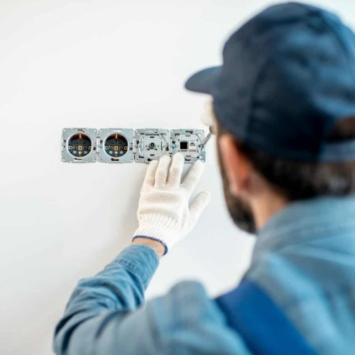 Electrician mounting sockets indoors